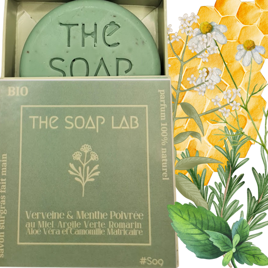 savon Verveine & Menthe Poivrée / The Soap Lab / dans boite en carton mi-ouverte vue de face et avec illustrations de plantes sur son côté droit. Fond transparent