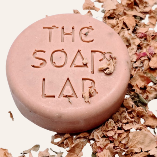 savon rose The Soap Lab sans boîte, vu de dessus avec des pétales de roses sur le côté. 