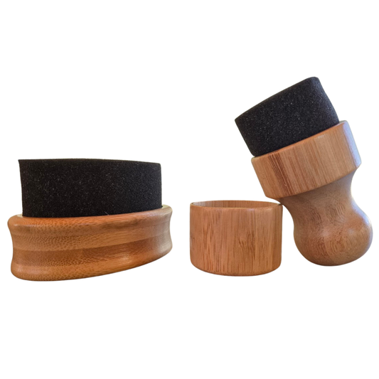 brosses mousse avec manches en bois sur fond blanc vues de face : une grande brosse ovale et une brosse ronde avec poignée en bois apposée sur un couvercle en bois. 